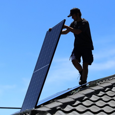 HDC owner installing a solar panel on a roof.