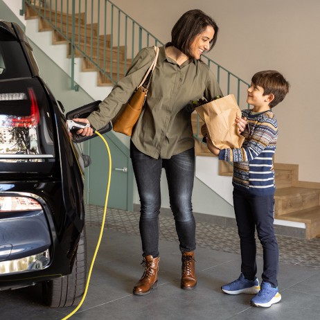 Mother and son using an electric vehicle charger at home.