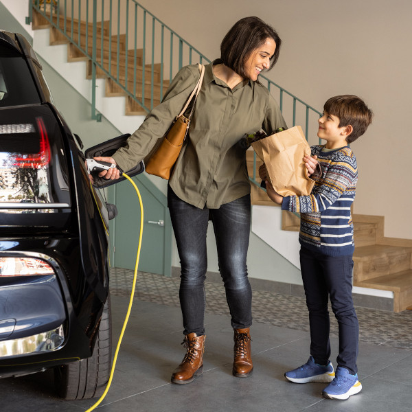 Mum using ev charger installation while her son holds groceries.