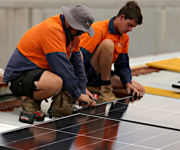 Two HDC staff installing a commercial solar panel in Melbourne.